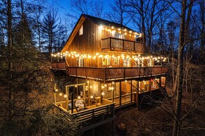 A wooden cabin with a balcony, string lights, and a deck. - Luxe Cabin, Dollywood, 4 min to Pkwy, Pups Welcome (Pigeon Forge)