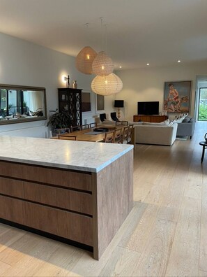 Enjoy a spacious kitchen and dining area with a central island, comfortable seating, and a large window offering a view of the outdoors.