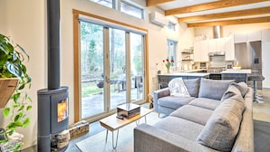 Een moderne woonkamer met een open haard, een bank en een eethoek, met een keuken op de achtergrond.