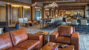 A modern hotel lobby with leather sofas, a wooden coffee table, and a long dining table. - Amazing One Bedroom suite w/sleeper sofa- Ski in/Ski out Grand Colorado Peak 8 (Breckenridge)