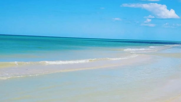 Una platja amb aigua turquesa cristal·lina i sorra daurada.