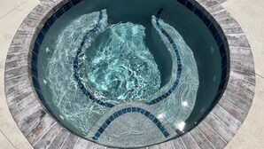 A hot tub with a tiled edge and a circular design, surrounded by a concrete deck. - Coastal Dream: New Heated Saltwater Pool/Hot Tub. Close to AMI, IMG, and LECOM. (Bradenton)