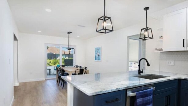 A modern kitchen with a large island, dark blue cabinets, and pendant lighting. - Coastal Dream: New Heated Saltwater Pool/Hot Tub. Close to AMI, IMG, and LECOM. (Bradenton)