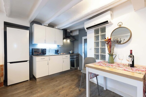 A compact kitchen with white cabinets, a built-in oven, and a dining area with a table set for two.