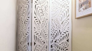 Een witte, gedetailleerd ontworpen roomdivider met bladmotieven.