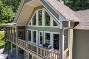 A two-story house with a balcony and a covered porch. - Family cabin with hot tub, mountain views, game room, near National Park! (Whittier)