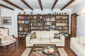 Ein Wohnzimmer mit einer Couch, einem Couchtisch und mehreren Bücherregalen, gefüllt mit Büchern und Dekoration.