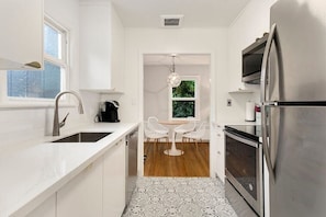 Una cocina moderna con armarios blancos, electrodomésticos de acero inoxidable y una isla central con sillas.