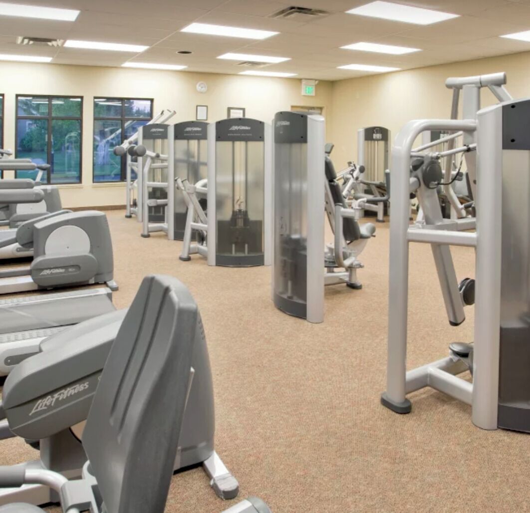 A gym with cardio machines, weight machines, and a mirrored wall.