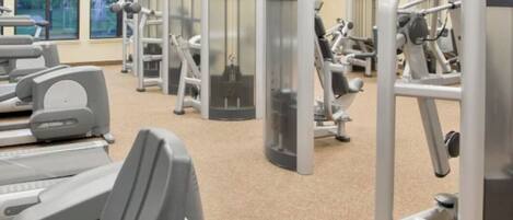 A gym with cardio machines, weight machines, and a mirrored wall.
