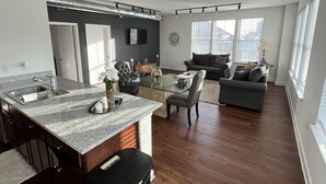 A modern kitchen with a granite countertop, stainless steel sink, and a dining area with a glass table and chairs. - Downtown Memphis Loft! Walking distance from Beale street! Garage parking! (Memphis)