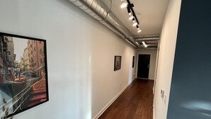 A hallway with wooden flooring, white walls, and artwork. - Downtown Memphis Loft! Walking distance from Beale street! Garage parking! (Memphis)