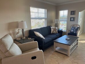 A living room with a sofa, armchair, coffee table, and lamps. - November/December availability: Waterfront corner unit, private patio, 1st floor (Indian Shores)