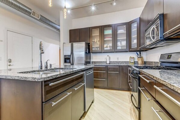 A modern kitchen with stainless steel appliances, granite countertops, and dark cabinetry. - Lovely 2-Bedroom Unit in Springfield (Springfield)
