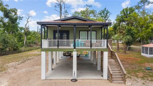 Ein zweistöckiges Haus mit Balkon, Veranda und einer Treppe, die zum oberen Stockwerk führt.