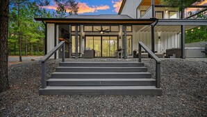 Ett modernt hus med en träveranda, en trappa som leder till en glasdörr och en takfläkt formad som en stjärna.