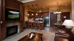 A modern kitchen with wooden cabinets, a central island, and a dining area with a table and chairs. - Grand Lodge Peak 7, Breckenridge 20-27 Dec, ski in/ski out resort 2 Bdrm/2 bath (Breckenridge)