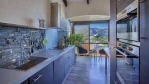 Cozinha moderna com painel de backsplash de pedra, eletrodomésticos de aço inoxidável e vista para montanhas através de grandes janelas.