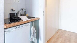 A compact kitchen with a built-in dishwasher, a small stove, and a sink. - Apartment Le Cocooning (Tours)