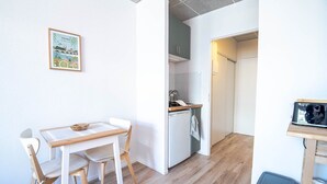 A compact living space with a dining area, kitchenette, and a small trash bin. - Apartment Le Cocooning (Tours)