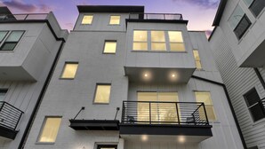 Een meerlaags woongebouw met een garage, een balkon met een hekwerk en een deur met een raam.