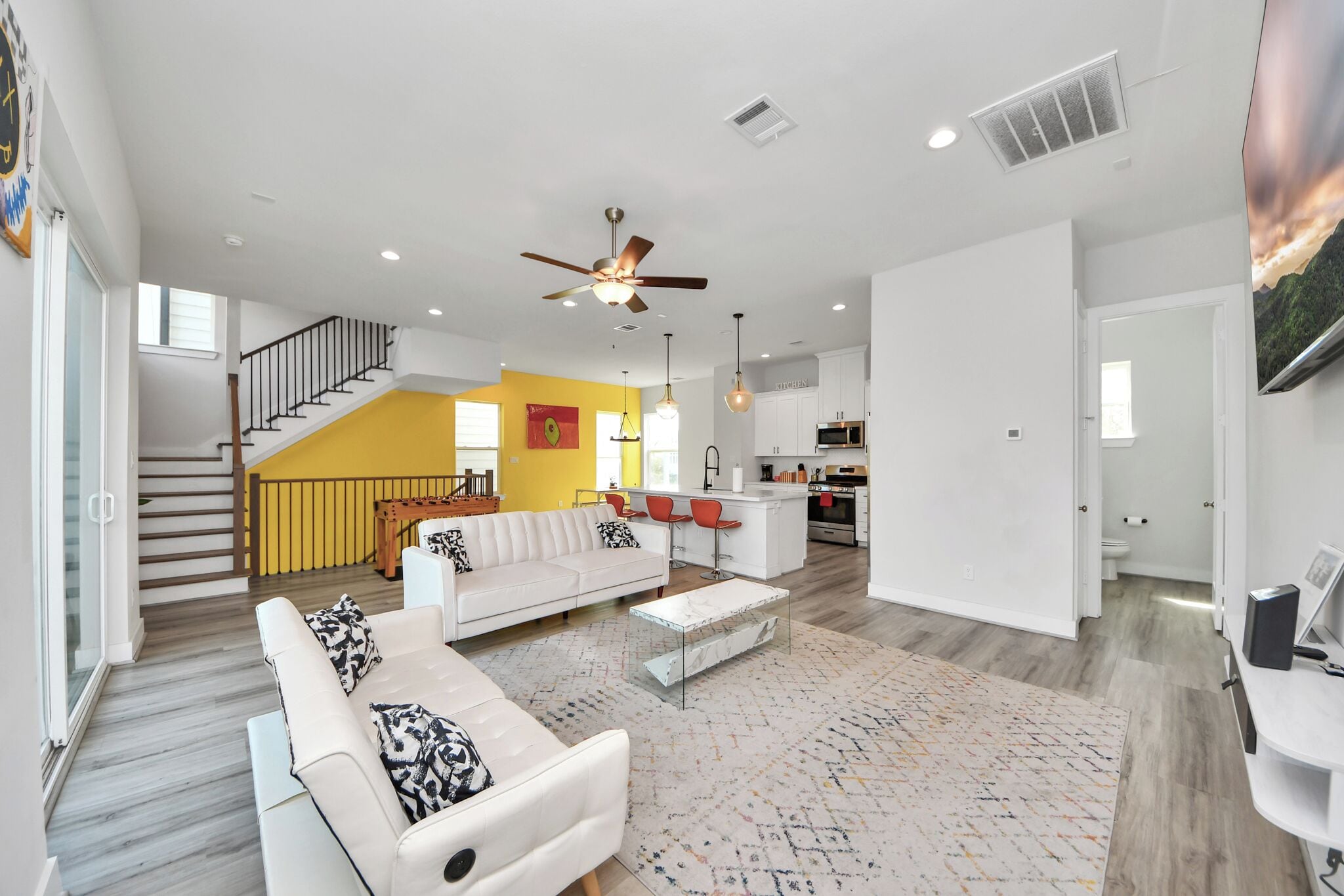 A spacious living area with a white sofa, a coffee table, and a kitchen in the background.