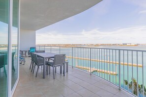 Enjoy breathtaking views of the water from this balcony with a table and chairs.