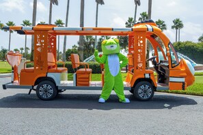A mascot in a green frog costume standing next to a vehicle with a ladder and orange seats. - Luxury 3BR/3BA CRC0405 in Orange Beach w/ bay views (Orange Beach)