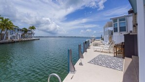 A waterfront property with a dock, lounge chairs, and a view of the sea. - Waterfront Venture Out Home (Cudjoe Key)