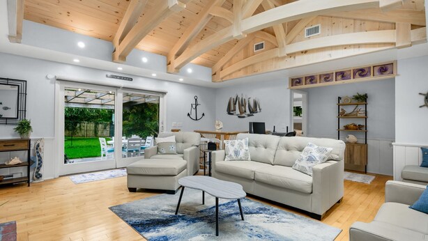 A spacious living room with a high ceiling, a large window, and a view of the outdoors.