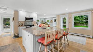 A modern kitchen with white cabinets, a granite countertop, and a central island with bar stools.
