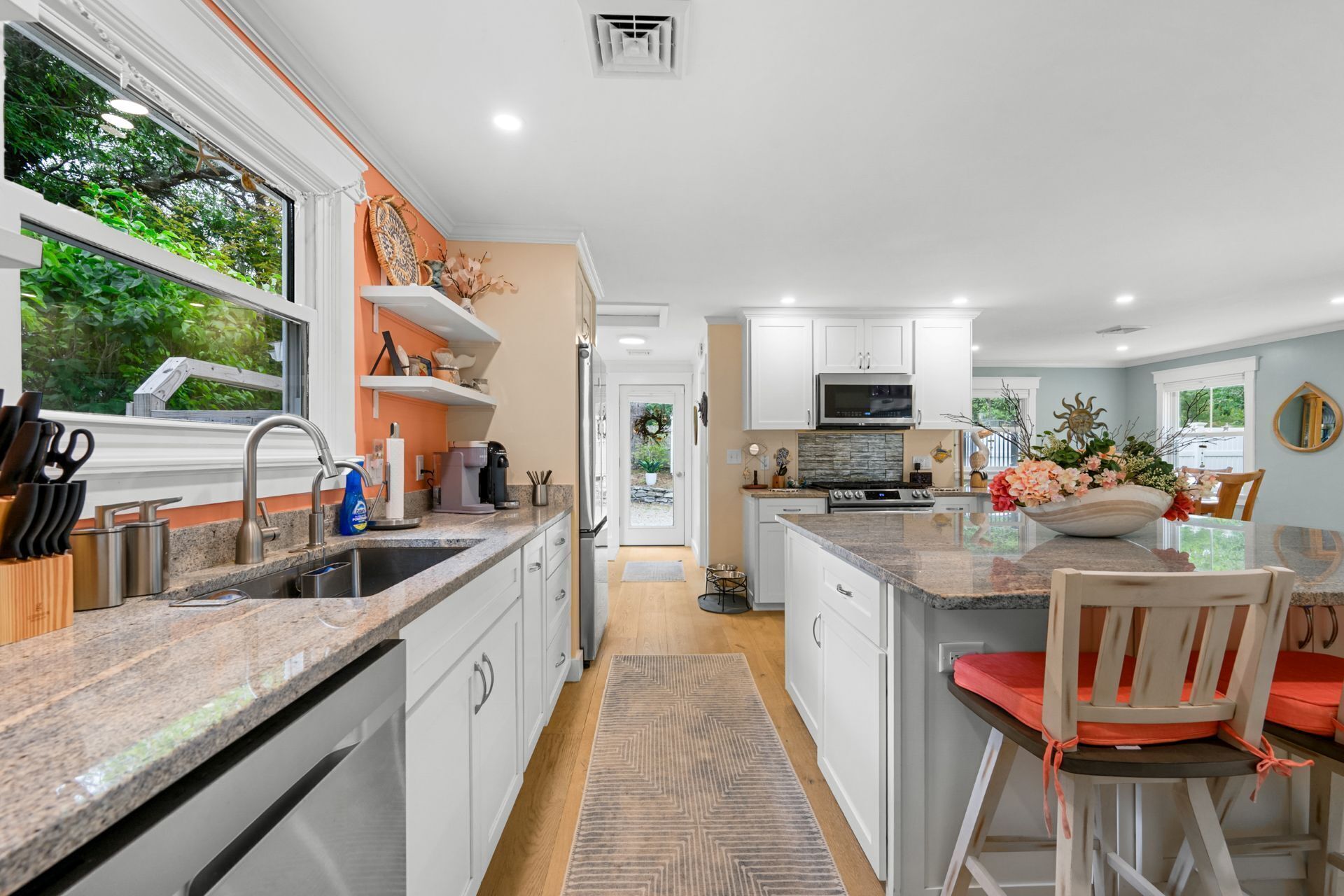 A modern kitchen with white cabinets, granite countertops, and a large island with seating.