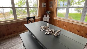 Una habitación con paneles de madera, una mesa grande y un banco, ventanas amplias y vistas al exterior.