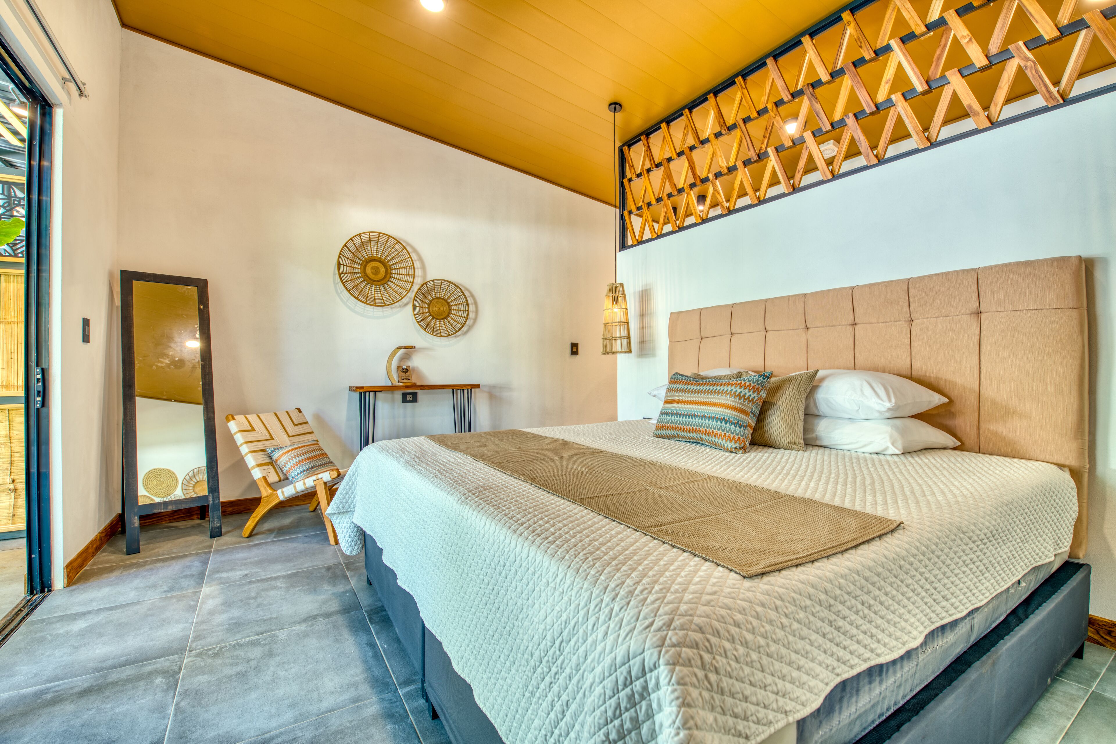 A bedroom with a large bed, a wooden headboard, a small table, and a mirror.