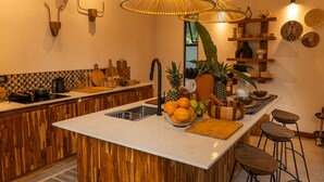 A modern kitchen with wooden accents, a central island with a sink, and a fruit bowl. - Exōtico Beach Hotel (Cahuita)