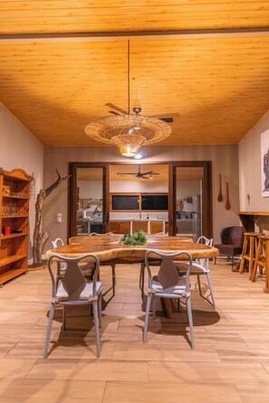 A dining area with a wooden table, metal chairs, a ceiling fan, and a wooden bookshelf.