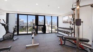 A gym with exercise equipment, large windows, and a city view.