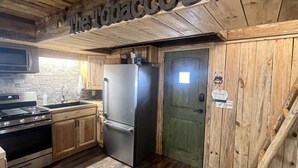 Una cocina rústica con paredes de madera, un refrigerador de acero inoxidable y una puerta de madera.