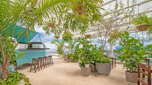 An indoor garden with potted plants, wooden stools, and a blue boat.