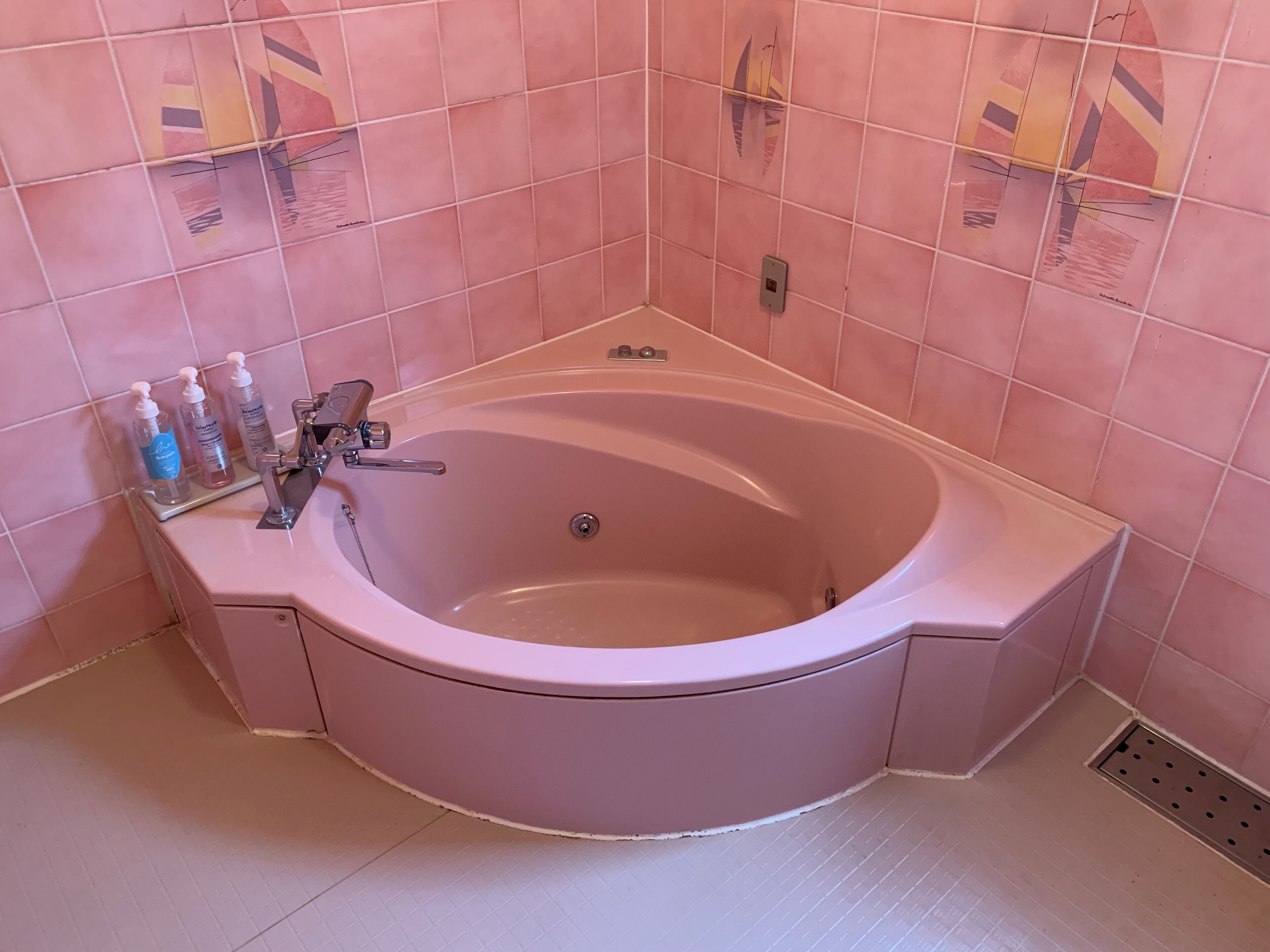 A bathroom with a freestanding bathtub, a vanity with a mirror, and a shelf with toiletries.