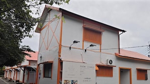 Fila de edificios blancos con detalles en naranja y un cartel publicitando un cargo por habitación disponible las 24 horas.