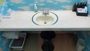 A bathroom with a sink, hand soap, and toiletries.