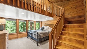 A bedroom with a wooden staircase, a bed, and large windows offering a view of trees. - Carpe Montem - Modern, Views, Large Deck, Hot Tub, Private (Sundance)
