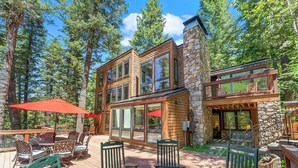 A modern wooden cabin with large windows and a stone chimney, surrounded by a deck with outdoor furniture and a fire pit. - Carpe Montem - Modern, Views, Large Deck, Hot Tub, Private (Sundance)
