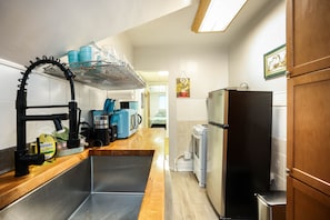 A kitchen with a stainless steel sink, a coffee machine, and a refrigerator.