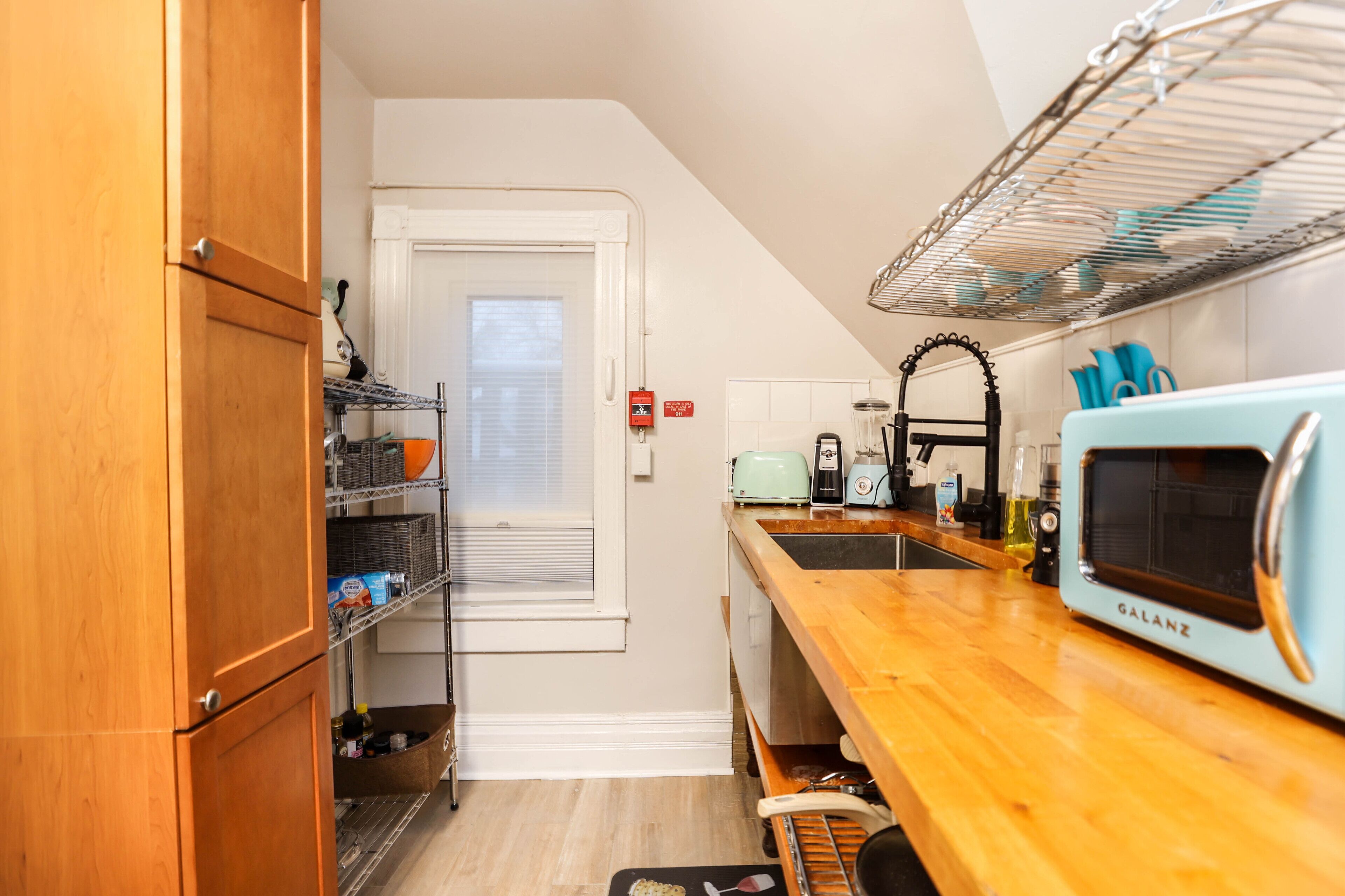 A compact kitchen with wooden cabinets, a microwave, and a sink.