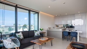A modern living room with a sofa, coffee table, and dining area. - A-402 Stunning one bedroom oceanview (Cupecoy)