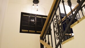 Una escalera con barandas de hierro negro y pared blanca.