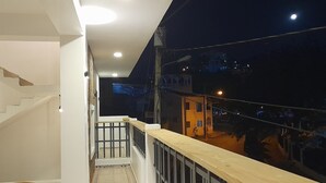 Un balcón con barandilla de madera, una mesita y una silla.
