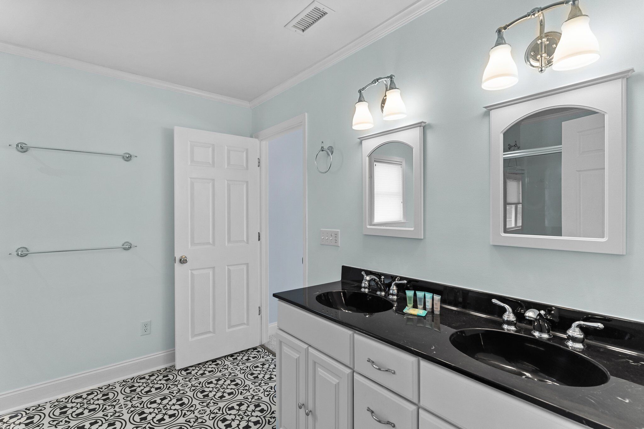 A bathroom with two sinks, a mirror, and a towel rack.